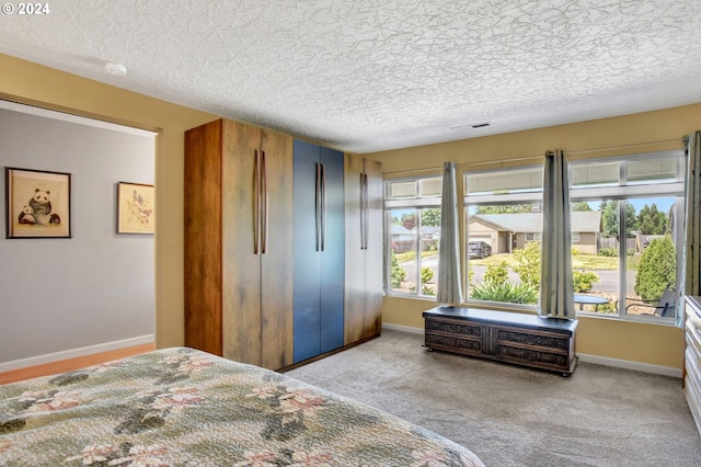 bedroom with a textured ceiling, light carpet, and multiple windows