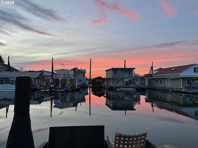 patio terrace at dusk featuring a water view and a boat dock