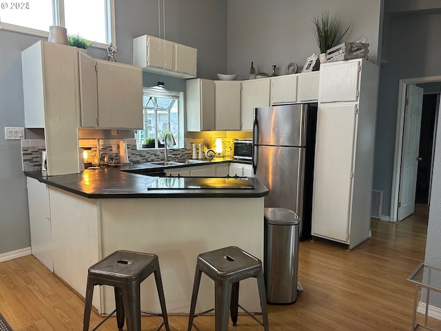 kitchen with stainless steel fridge, light hardwood / wood-style floors, sink, and backsplash