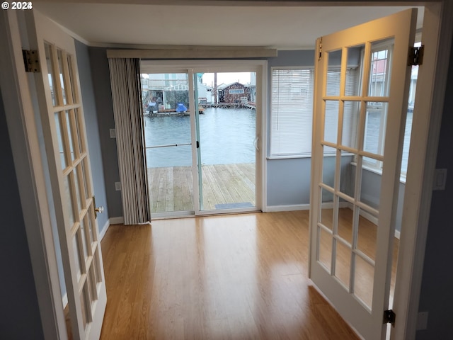 interior space with a water view, wood-type flooring, and french doors