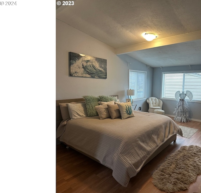 bedroom with vaulted ceiling with beams, hardwood / wood-style flooring, and a textured ceiling