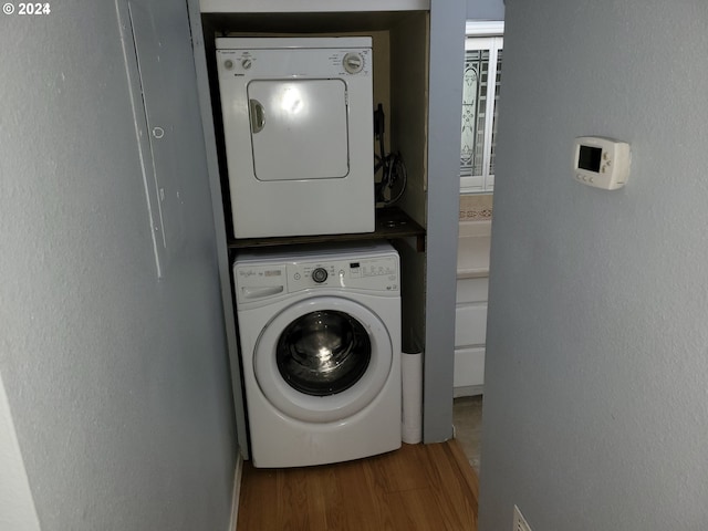 washroom with hardwood / wood-style floors and stacked washer / dryer