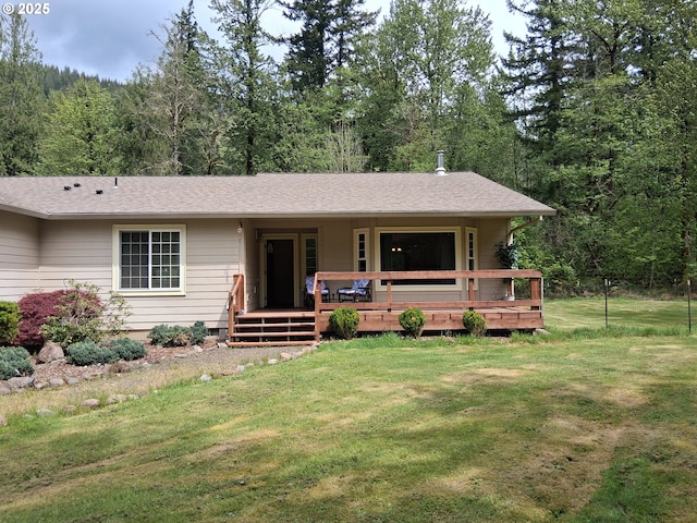 view of front facade with a front yard, a forest view, and roof with shingles