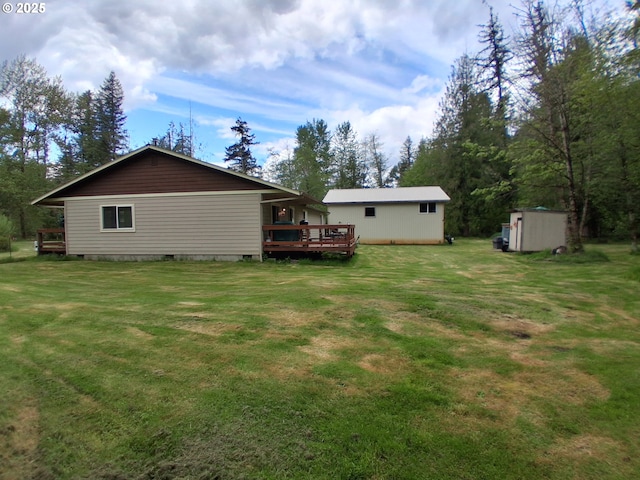 back of property with an outdoor structure, a wooden deck, a shed, and a lawn