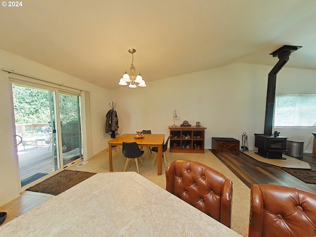 dining area featuring a wood stove, a wealth of natural light, lofted ceiling, and a notable chandelier