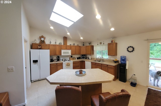 kitchen featuring white appliances, a sink, light countertops, recessed lighting, and a skylight