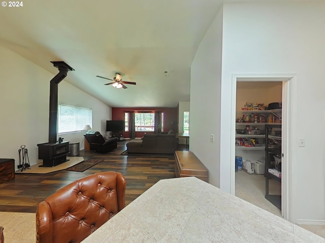 bedroom with a wood stove, vaulted ceiling, wood finished floors, and a walk in closet