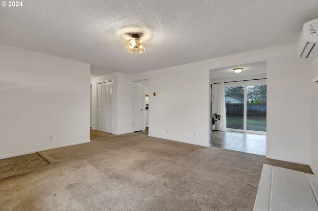 unfurnished room with carpet floors, an AC wall unit, and a textured ceiling