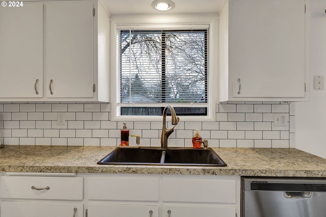 kitchen with white cabinetry, sink, stainless steel dishwasher, and decorative backsplash