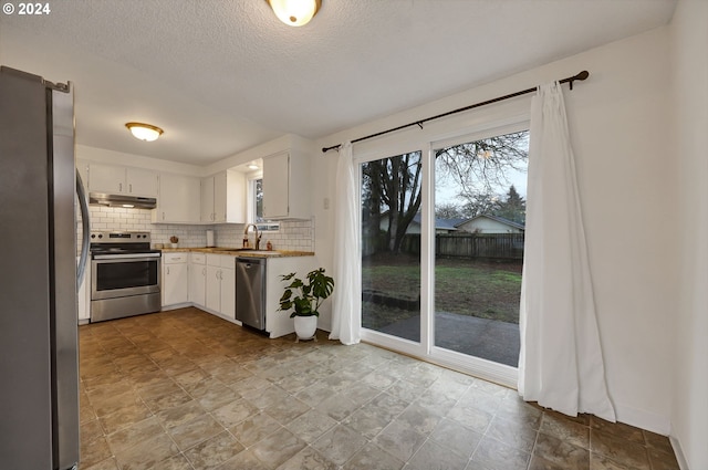 kitchen featuring sink, stainless steel appliances, tasteful backsplash, a textured ceiling, and white cabinets