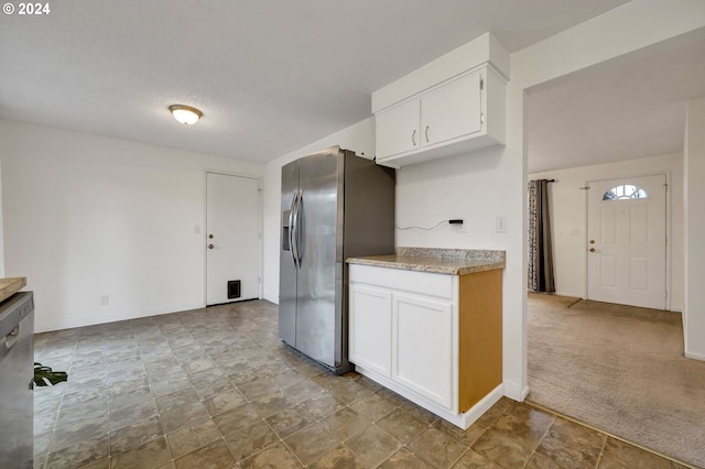 kitchen with stainless steel appliances, white cabinetry, carpet flooring, and a textured ceiling