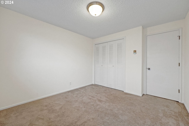 unfurnished bedroom with a closet, light carpet, and a textured ceiling