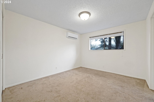 carpeted empty room featuring a wall mounted air conditioner and a textured ceiling