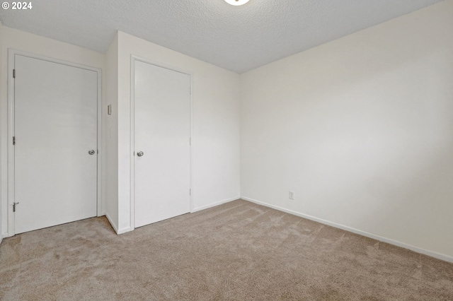 unfurnished bedroom with light carpet, a textured ceiling, and a closet