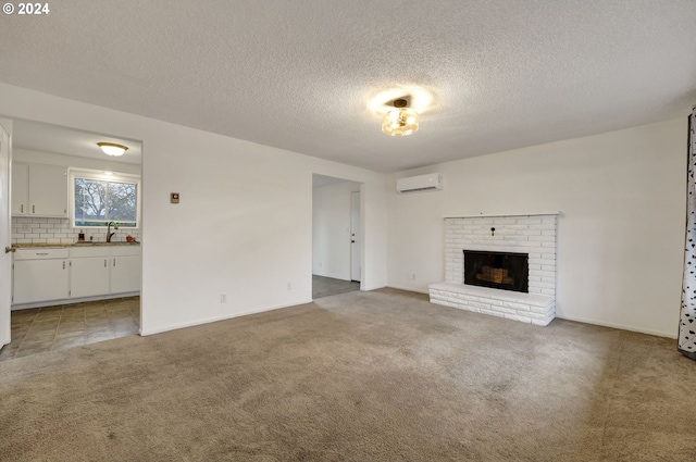 unfurnished living room featuring sink, a wall mounted air conditioner, a brick fireplace, a textured ceiling, and carpet floors