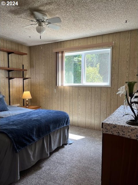 46791 Winfrey Rd, Westfir, OR 97492 - bedroom featuring wooden walls, carpet flooring, a textured ceiling, and ceiling fan