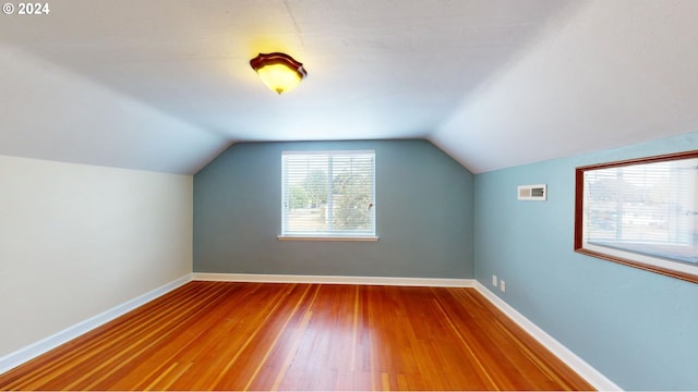 additional living space featuring vaulted ceiling and hardwood / wood-style flooring