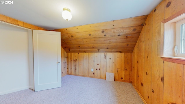 bonus room with lofted ceiling, wood walls, and light colored carpet