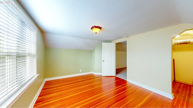 unfurnished room with wood-type flooring, vaulted ceiling, and a healthy amount of sunlight