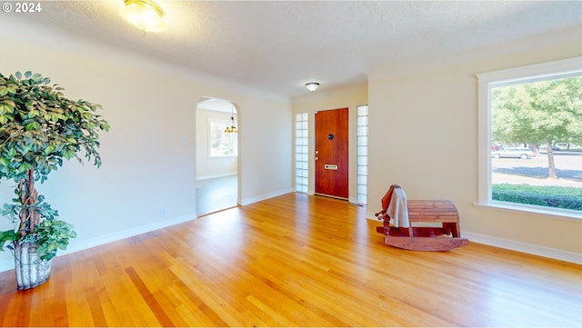 empty room with a healthy amount of sunlight, a textured ceiling, and hardwood / wood-style floors