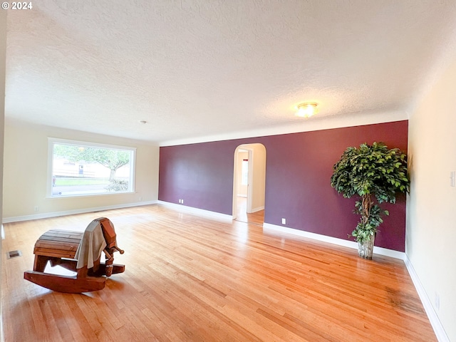 empty room featuring a textured ceiling and light hardwood / wood-style floors