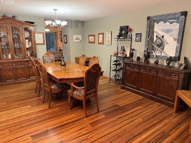 dining room featuring a notable chandelier, wood-type flooring, and a textured ceiling