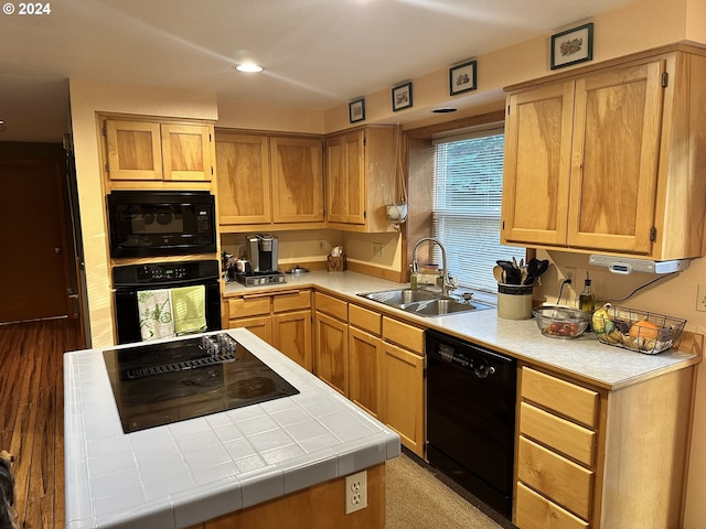 kitchen with light hardwood / wood-style flooring, black appliances, sink, and tile counters