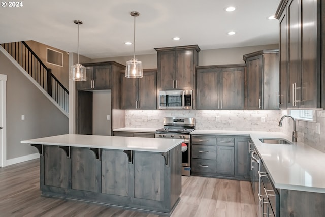 kitchen featuring decorative light fixtures, appliances with stainless steel finishes, sink, and a center island