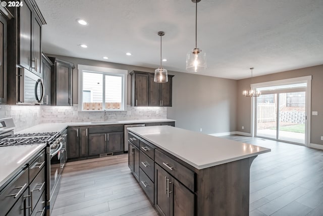 kitchen featuring light hardwood / wood-style floors, a center island, hanging light fixtures, sink, and appliances with stainless steel finishes