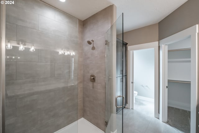 bathroom featuring tile patterned flooring, toilet, and a shower with door