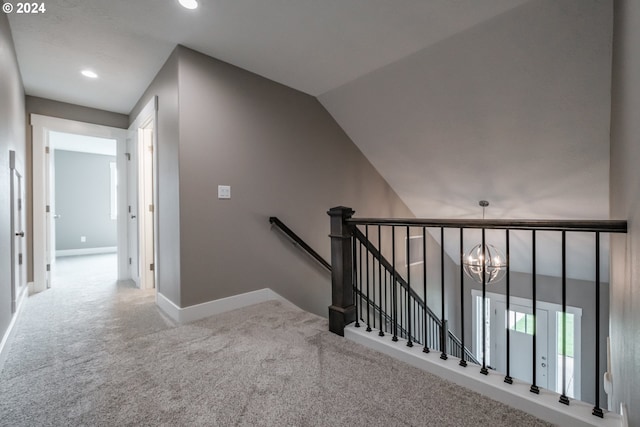 staircase with a chandelier, vaulted ceiling, and carpet flooring