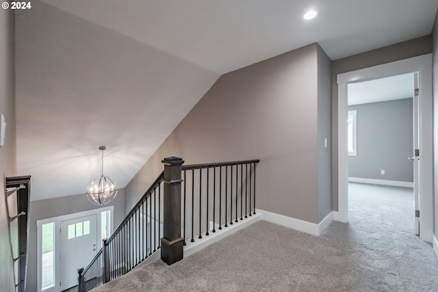 staircase featuring lofted ceiling, a notable chandelier, and carpet floors