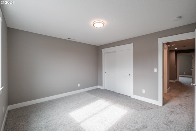 unfurnished bedroom featuring light colored carpet and a closet