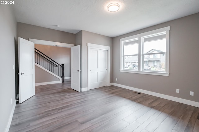 unfurnished bedroom with a closet, a textured ceiling, and light hardwood / wood-style flooring