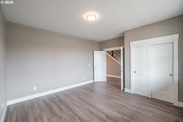 unfurnished bedroom with a textured ceiling, a closet, and light wood-type flooring