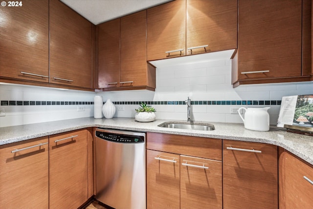 kitchen featuring light stone counters, dishwasher, sink, and decorative backsplash