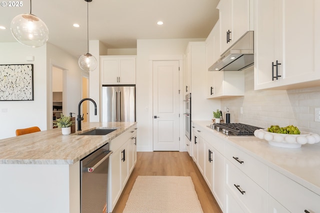 15044 SW 164th Ave Unit L17, Tigard, OR 97224 - kitchen featuring appliances with stainless steel finishes, under cabinet range hood, light wood finished floors, backsplash, and hanging light fixtures