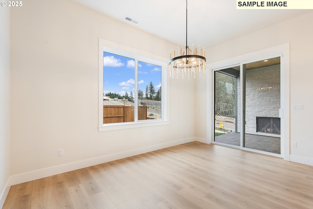 unfurnished room with wood finished floors, a fireplace, baseboards, and a healthy amount of sunlight