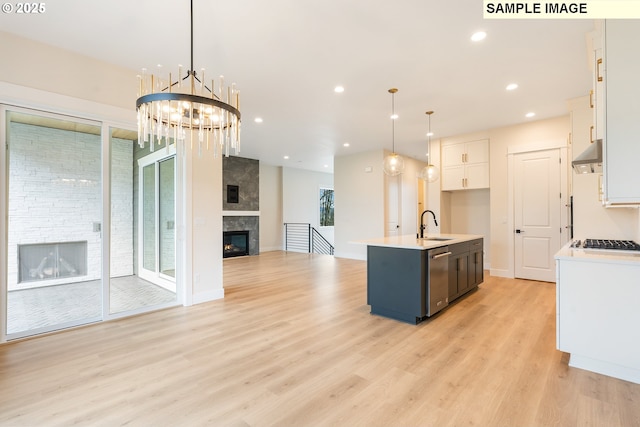 kitchen with a fireplace, light countertops, white cabinets, under cabinet range hood, and open floor plan