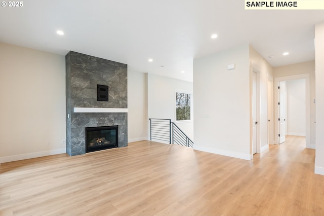 unfurnished living room with recessed lighting, wood finished floors, baseboards, and a high end fireplace