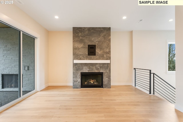 unfurnished living room with recessed lighting, wood finished floors, baseboards, and a tile fireplace