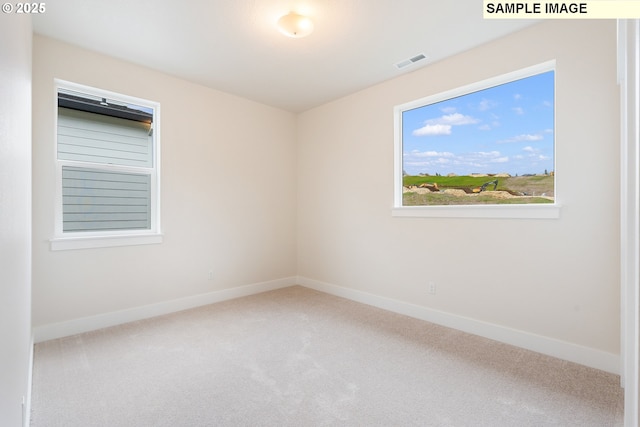 carpeted spare room with visible vents and baseboards