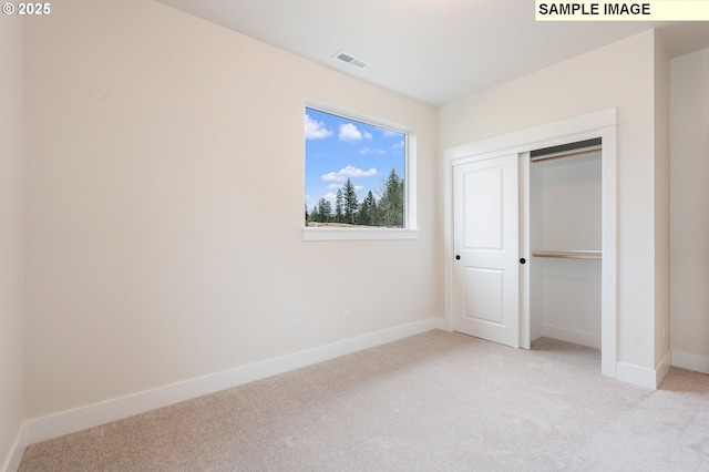 unfurnished bedroom with visible vents, light carpet, baseboards, and a closet