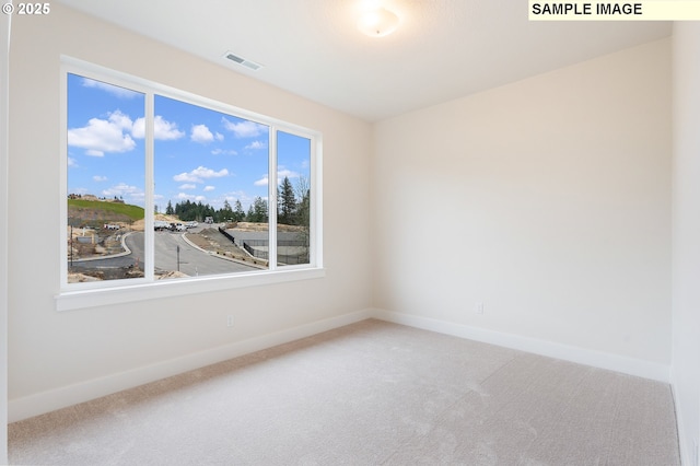 carpeted spare room with visible vents and baseboards