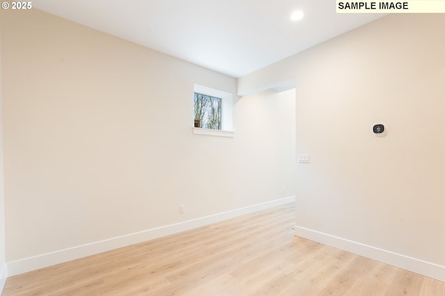 spare room featuring light wood finished floors, recessed lighting, and baseboards