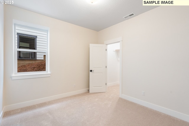 unfurnished room featuring light colored carpet, visible vents, and baseboards