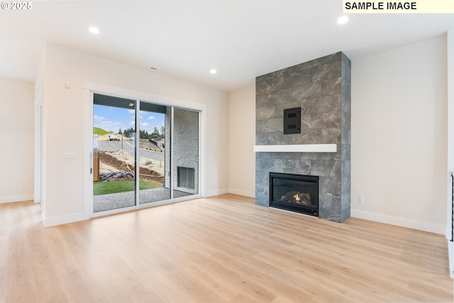 unfurnished living room with recessed lighting, a tile fireplace, and wood finished floors