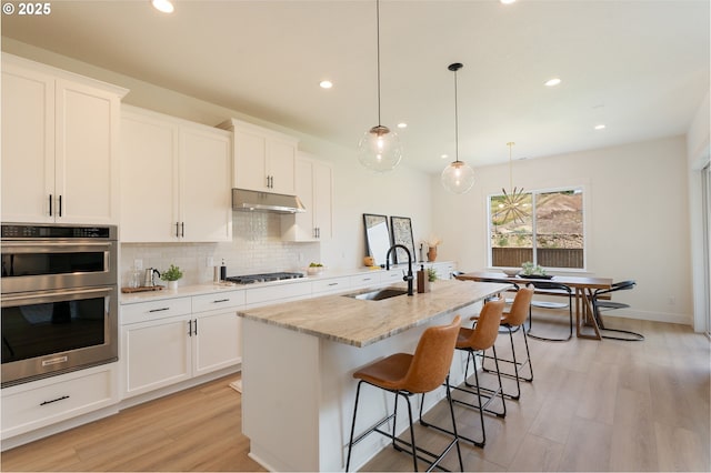 15044 SW 164th Ave Unit L17, Tigard, OR 97224 - kitchen with stainless steel double oven, tasteful backsplash, light wood finished floors, recessed lighting, and under cabinet range hood