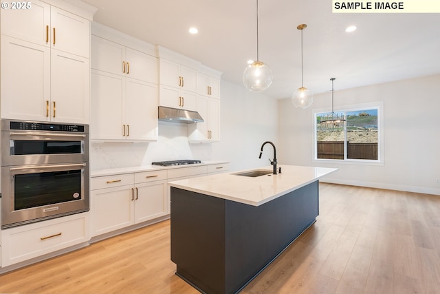 kitchen with gas cooktop, a sink, under cabinet range hood, double oven, and light wood-type flooring