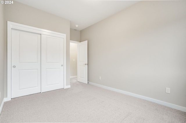 unfurnished bedroom with light colored carpet and a closet